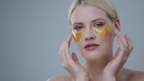 Woman Applying Gold Cosmetic Eye Patches