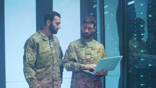 Two Men in Camouflage with Laptop near Servers