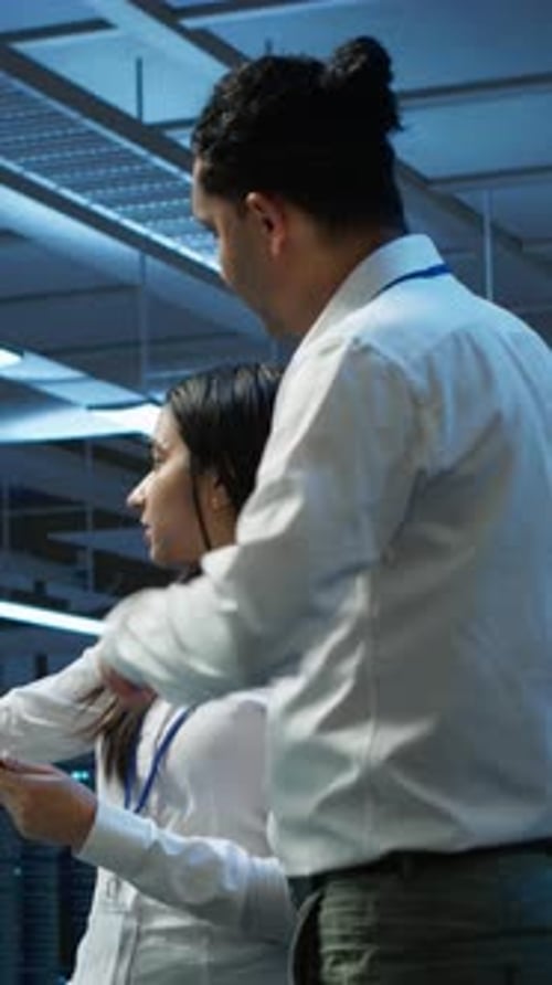 Technicians Review Data on Tablet in Server Room