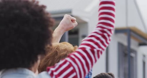 Back view of diverse group of protesters with raised hands screaming