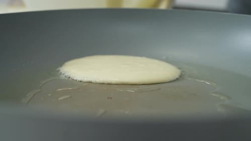 Close-up pouring sticky pancake batter into a hot frying pan