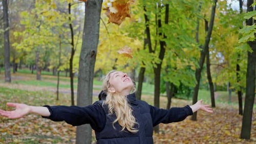 Cheerful Beautiful Woman Throws Yellow Leaves in an Autumn Park