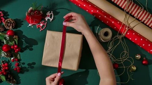 Hands Tying Red Ribbon on a Christmas Gift