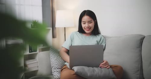 Young woman uses laptop to shop online on sofa at home.