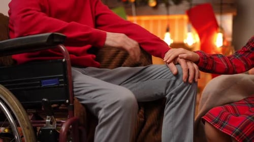 Girl Holding Hands with Senior Man in Wheelchair