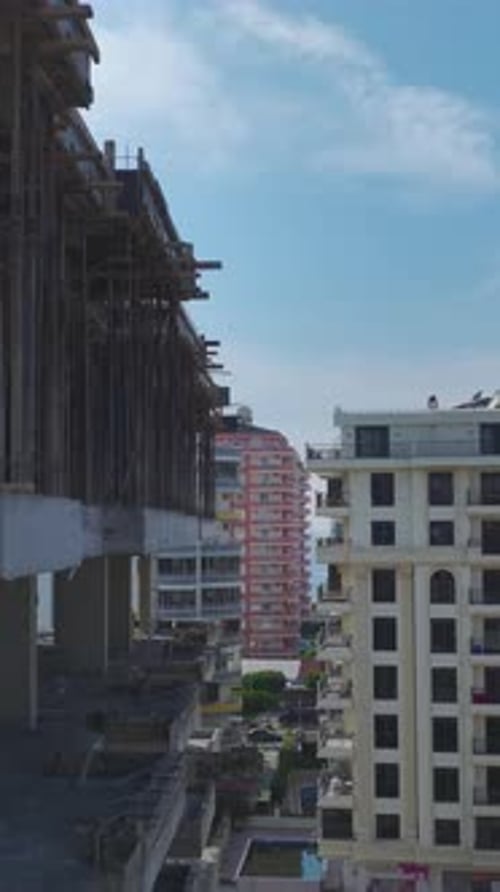 Los ingenieros de vídeo vertical supervisan los planes mientras los equipos construyen paredes, manipulan el metal y vierten hormigón sobre un