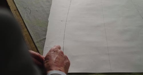 A tailor drawing and cutting a cloth according to the tradition of tailors. The dressmaker uses pe