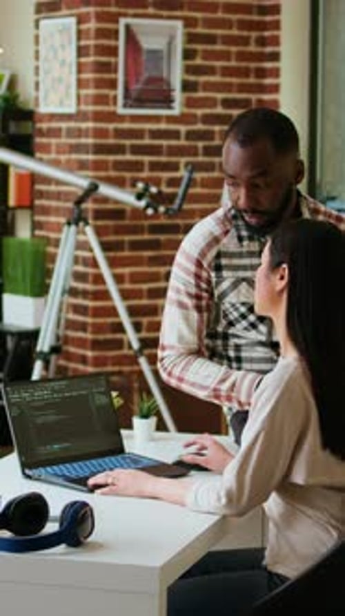 Vertical Video Interracial Creative Team Programing Code on a Laptop and Debugging