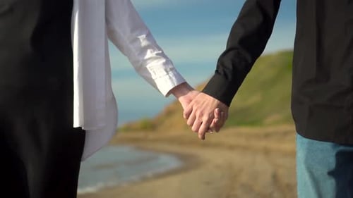A Couple Holding Each Others Hands on the Beach While Watching a Beautiful Sunset