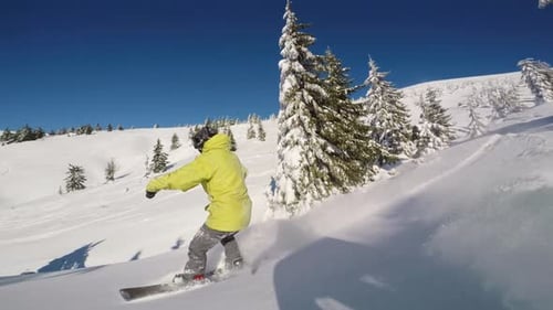 Zeitlupenaufnahme eines Snowboarders an einem strahlend sonnigen Tag beim Cruisen den Berg hinunter