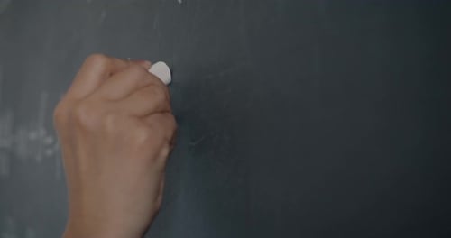 Hand Writes Math Equations on Chalkboard