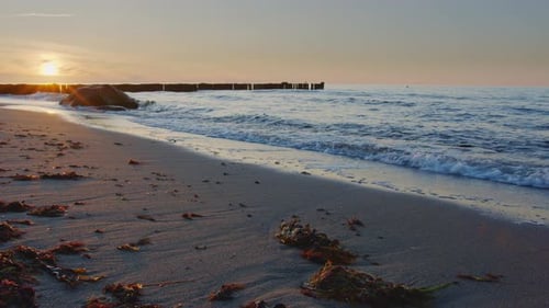 Beach with small waves while beautiful sunset, wide angle,