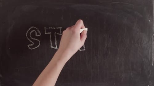 Hand Writes 'Stay Home' on Chalkboard with House
