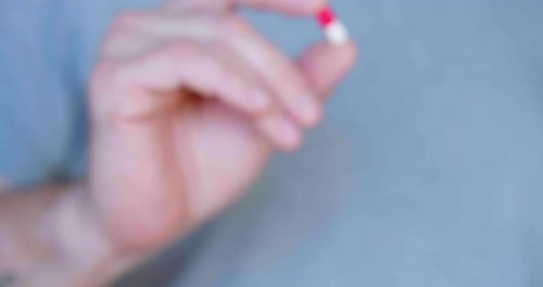Red and White Capsule in the Hands of a Person