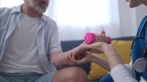 Senior man exercising wrist with physical therapist support