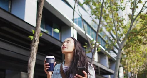 Woman Drinking Coffee and Using Smartphone in City