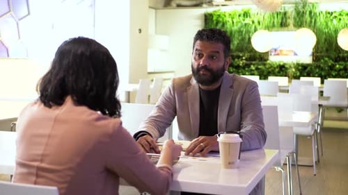 Business People Reviewing Paperwork In Office Cafeteria