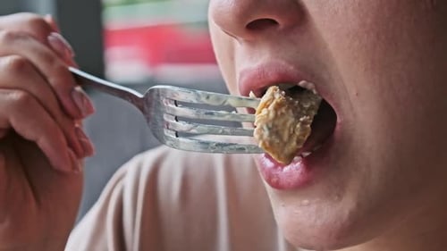 Woman Eating Meat in Restaurant