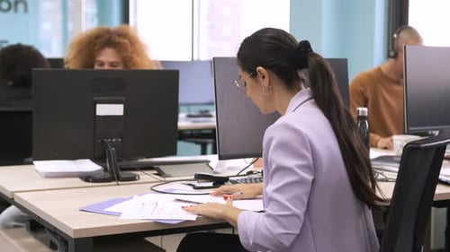 Woman Reviews Documents at a Modern Office Desk