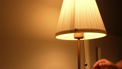Eine Hand macht die warmgelbe Lampe aus.