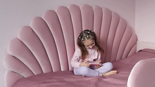 Child Plays with a Phone on Bed