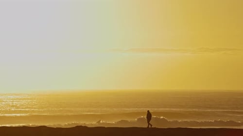 A Lonely Man Walking By the Sea at Bright Orange Sunset