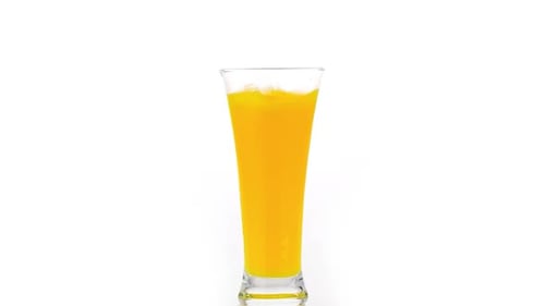 Orange Liquid Splashes in Glass Cup on White