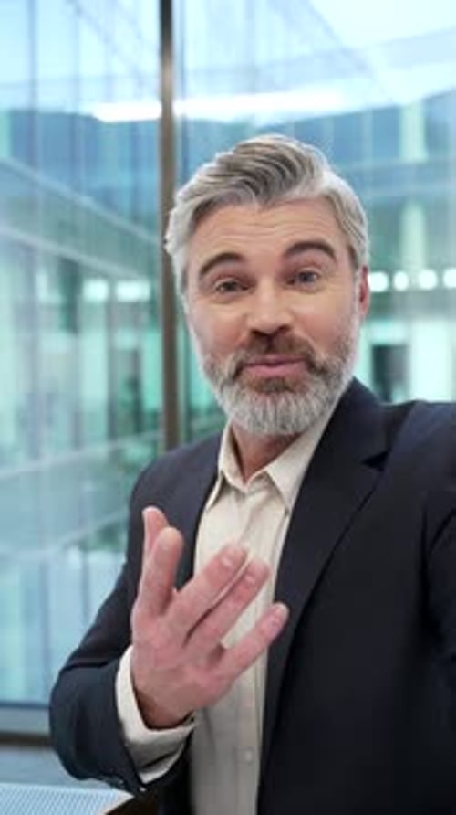 POV Vertical. Smiling businessman talking on a video call using phone in office. Male entrepreneur