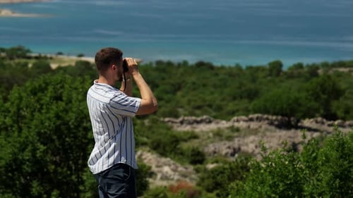 Junger Mann mit Fernglas mit Blick auf die Adriaküste in Kroatien