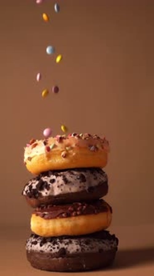 Slow Motion Donut Stack with Falling Colorful Candy Pieces
