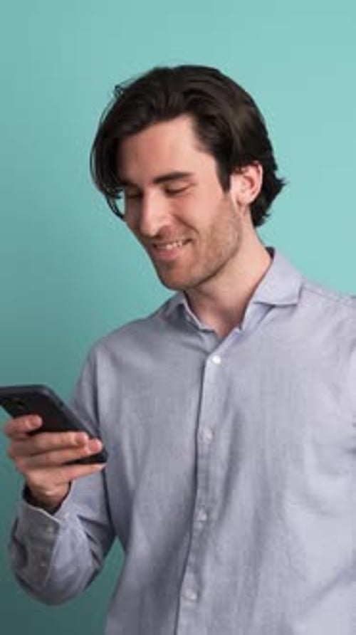 Smiling Adult Man Using Smartphone in Blue Studio