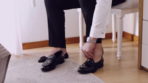 Man Adjusts Black Loafer, Preparing Formal Attire
