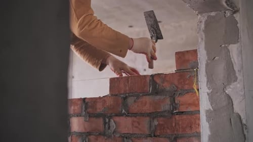 Construction Worker Lays Bricks on Wall