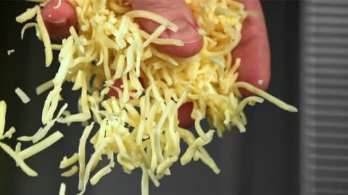 Geriebener Käse fällt dem Koch aus der Hand, gefilmt mit einer Hochgeschwindigkeitskamera mit 1000 Bildern pro Sekunde