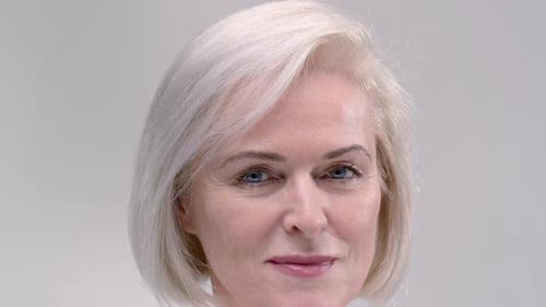 Pretty Senior Woman with Short Haircut Smiles Turning Head on Light Grey Background Closeup