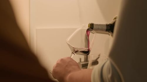 Mann gießt Gläser mit Rotwein ein, während er zu Hause mit einer Freundin ausgeht