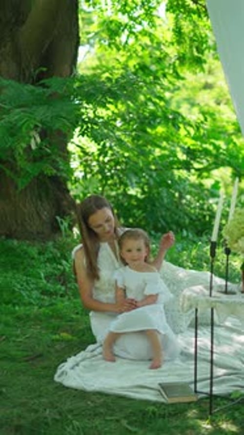 Mother Sitting on a Blanket with Her Little Daughter in the Park Concept of a Moment of Love and