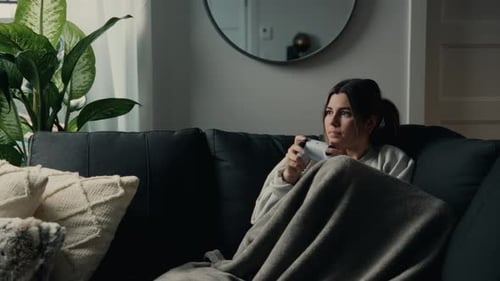 A Young Woman, Holding a Controller, is Absorbed in Her Game in a Cozy Setting - Close Up