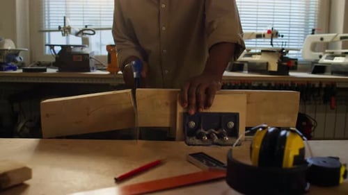 Woodworker Using Handsaw for Cutting Timber in Carpentry Workshop