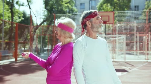 Active Senior Couple Exercising Outdoors on Basketball Court