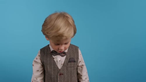 Portrait d'un mignon petit garçon souriant en costume de vacances avec papillon sur fond de studio bleu