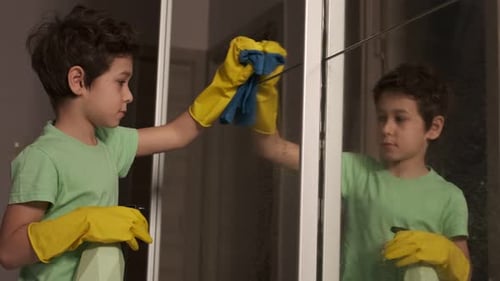 Boy with Inspiration Cleans the House Washes the Mirror with a Spray and a Sponge the Mantesori