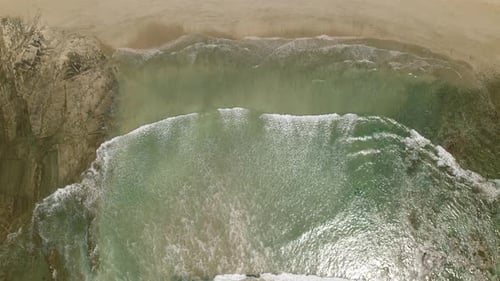 Aerial view of gentle sea waves approaching sandy tropical beach on sunny day
