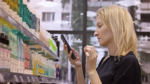 Purchase in cosmetics store Scanning QR code from bottle on smartphone,