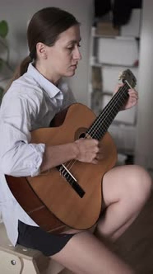 Woman plays guitar at home