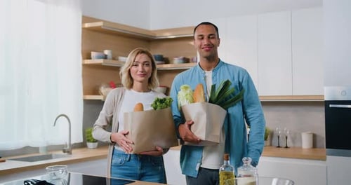 Couple Holds Grocery Bags in Modern Kitchen