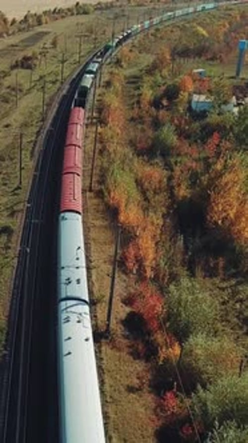 a long freight train with building materials is moving by railway