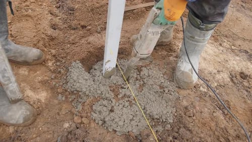 Construction Workers Securing Pole with Power Tool