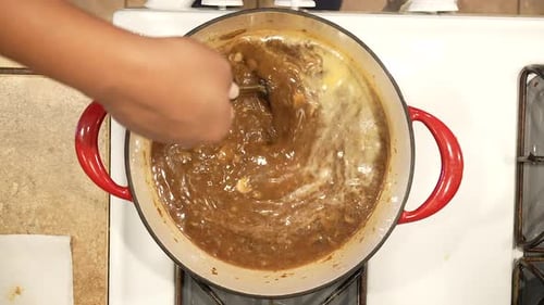 Stirring wild rice mushroom soup as it boils in a pot on the stove in slow motion - overhead view WI