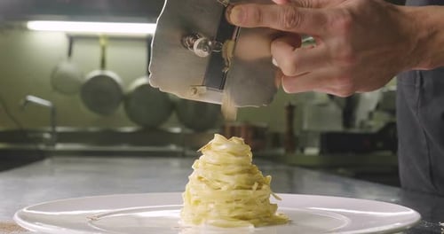 Chef Grating Truffle over Pasta in Kitchen